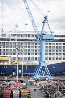A crane is in front of a cruise ship on the shipyard site